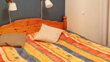 A bed with a colorful striped bedspread, two bedside lamps, and a pillow.
