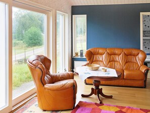 Une pièce avec deux fauteuils en cuir, une table basse en bois et une vue sur la verdure environnante.