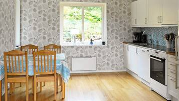 A kitchen with white cabinets, a built-in oven, and a window with a view of greenery.