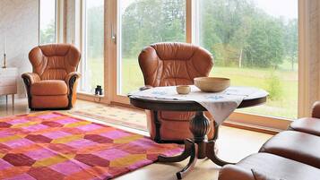 A room with two leather chairs, a round table with a bowl, and a colorful rug.