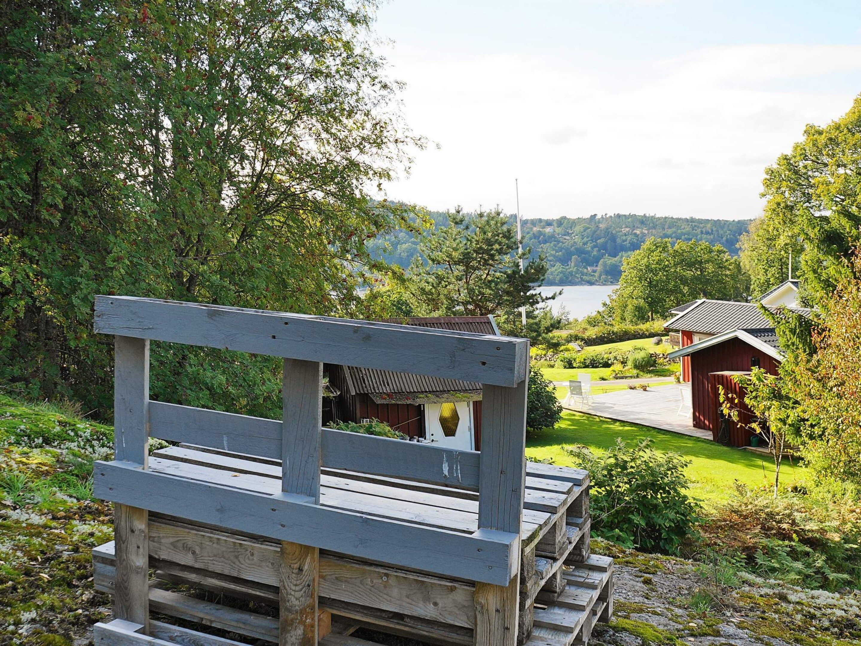 A wooden bench overlooking a lake with a red building in the background.