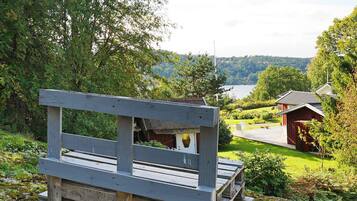 A wooden bench overlooking a lake with a red building in the background.