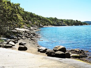 A rocky shoreline with clear blue water and dense green trees. - Holiday Home in Ljungskile (Ljungskile)