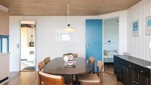 A dining area with a round table, six chairs, a hanging light fixture, and a blue door. - 4 Person Holiday Home in Borkop (Borkop)