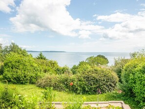 A coastal landscape with dense greenery and a view of the sea.