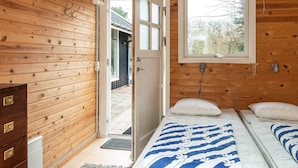Una habitación tipo cabaña de madera con una cama, un tocador y una ventana.