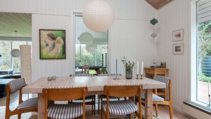 Un comedor con una mesa y sillas de madera, una lámpara colgante y un cuadro en la pared.