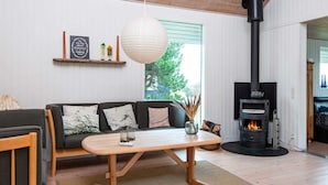Una sala de estar moderna con un sofá, una mesa de centro de madera, una chimenea y un ventanal grande.