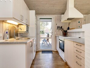 A modern kitchen with white cabinetry, stainless steel appliances, and a wooden floor. - Cozy Holiday Home in Jutland near Beach (Hals)