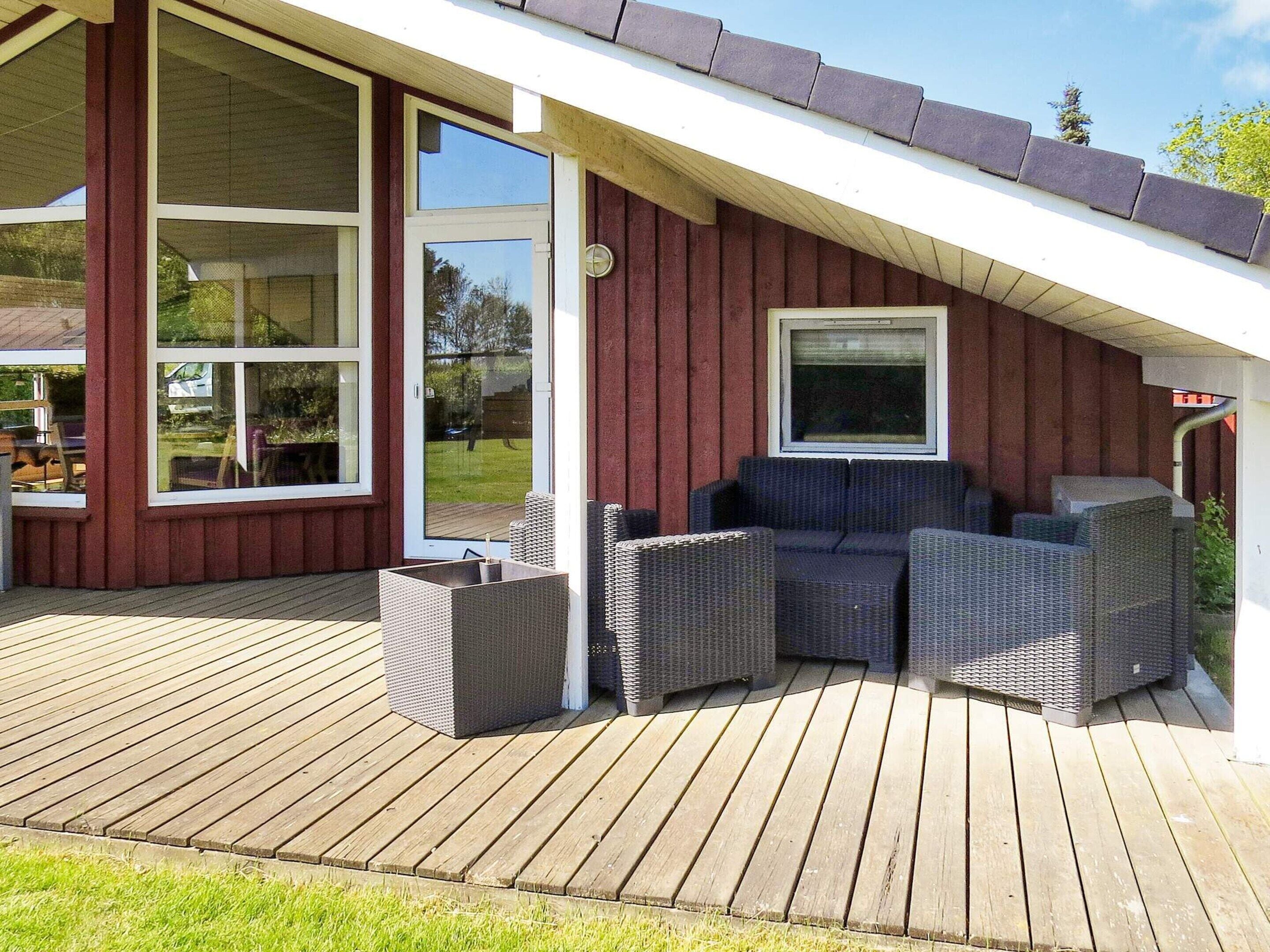 An outdoor deck with wicker furniture and a sliding glass door leading to a backyard.