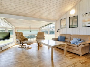 A cozy living room with a wooden ceiling, a leather sofa, two armchairs, a coffee table, and a television. - Cozy Holiday Home in Jutland near Beach (Hals)