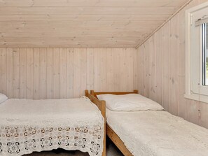 A small, single-room cabin with two wooden beds and a window.