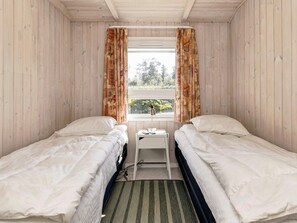 A room with two beds, a small table, and a window with curtains. - Cozy Holiday Home in Jutland near Beach (Hals)