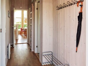 A hallway with a metal rack holding an umbrella, a dining area with chairs and a table, and a view of the outdoors through a door. - Cozy Holiday Home in Jutland near Beach (Hals)