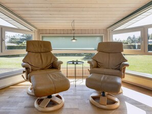 Two leather chairs with wooden bases in a room with large windows and a view of the outdoors. - Cozy Holiday Home in Jutland near Beach (Hals)