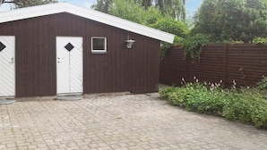 A building with two doors, a small window, and a paved driveway.