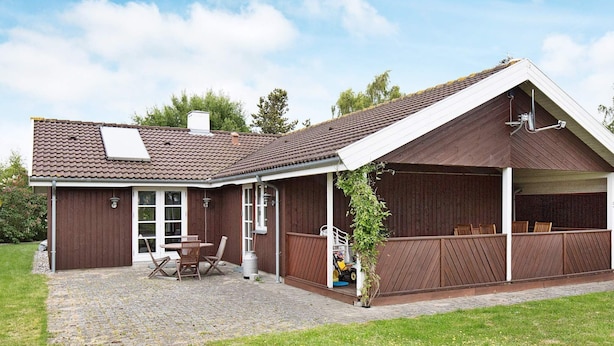 A two-story house with a covered patio, a chimney, and a small garden area.