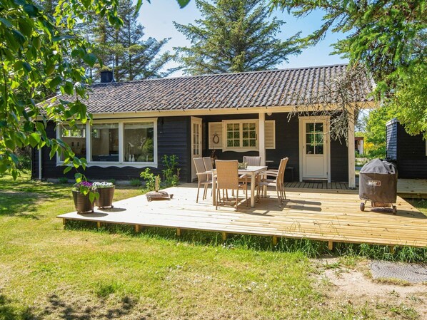 A wooden deck with outdoor furniture, a grill, and a small garden area with potted plants.
