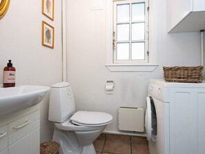 A compact bathroom with a toilet, sink, and washing machine.
