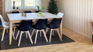 Un comedor con una mesa de madera, sillas negras y un tapete de diseño blanco y negro.