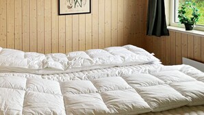 Una cama grande con cubrecama acolchada e ilustración botánica enmarcada en la pared.