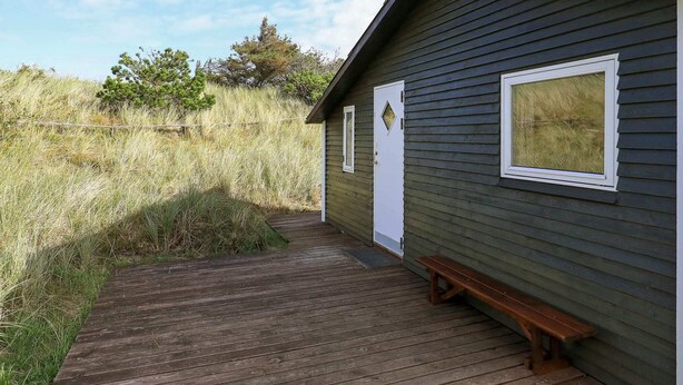 A wooden deck leading to a small cabin with a bench and a door. - 5 Person Holiday Home in Ringkobing-by Traum (Ringkobing)