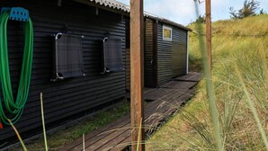 A wooden cabin with a corrugated metal roof, a small window, and a door. - 5 Person Holiday Home in Ringkobing-by Traum (Ringkobing)