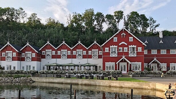 Un conjunto de edificios blancos y rojos con un muelle y agua frente a ellos.