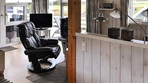 Una sala moderna con un sillón de cuero, un televisor de pantalla plana y un comedor con mesa y sillas.