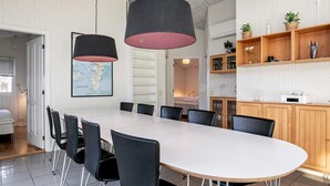 Ein moderner Essbereich mit einem langen Tisch, schwarzen Stühlen und Pendelleuchten.