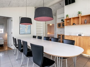 Un espace de restauration moderne avec une longue table, des chaises noires et des luminaires suspendus.