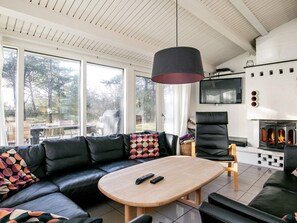 A modern living room with a leather sofa, a wooden coffee table, and a fireplace. - 16 Person Holiday Home in Humble (Sydlangeland)
