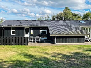 A building with a flat roof, a covered patio area with outdoor seating, and a fenced yard. - 4 Star Holiday Home in Tarm (Tarm)