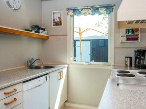 A compact kitchen with a dishwasher, a sink, a stove, and a window with a view of a building outside. - 4 Star Holiday Home in Tarm (Tarm)