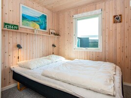 Un dormitorio con cama, ventana, un cuadro y una placa de matrícula en la pared.