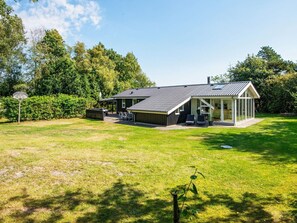 A house with a covered patio, a fenced yard, and a basketball hoop. - 4 Star Holiday Home in Tarm (Tarm)