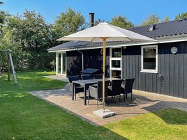 Un patio con mesa y sillas, una parrilla y un espacio cubierto con una sombrilla.