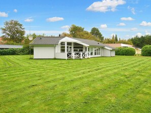 A white building with a covered patio and a fenced area.