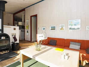A cozy living room with a sofa, a coffee table, a fireplace, and framed pictures on the wall.