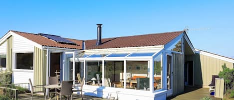 A modern house with a glass conservatory, a wooden deck, and a garden.