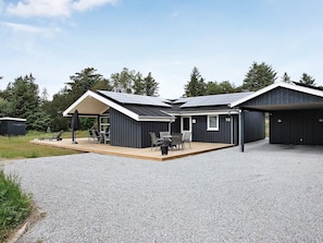 En modern byggnad med en inglasad uteplats, ett garage och en husnummerplakett med siffran 16.