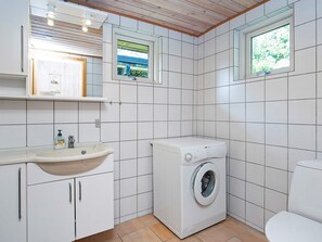 Une petite salle de bain comprenant un lavabo, un miroir, une fenêtre et un lave-linge.