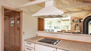 A kitchen with a granite countertop, white cabinetry, and a stainless steel range hood.