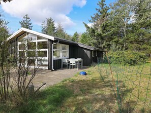Un petit bâtiment d’un seul étage, doté d’un patio couvert, d’une table et de chaises.