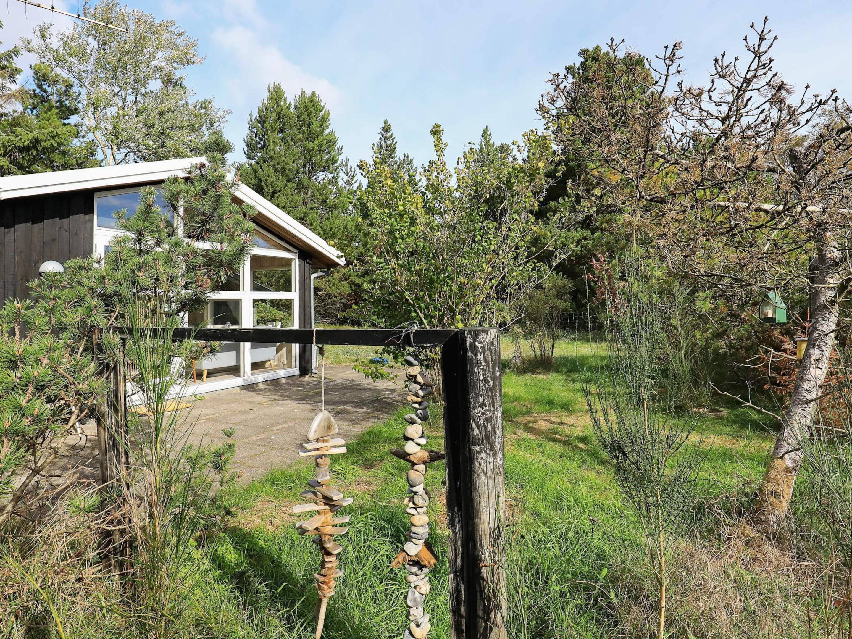 A rustic wooden fence with a stone wall and a house with large windows.