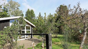 A rustic wooden fence with a stone wall and a house with large windows.