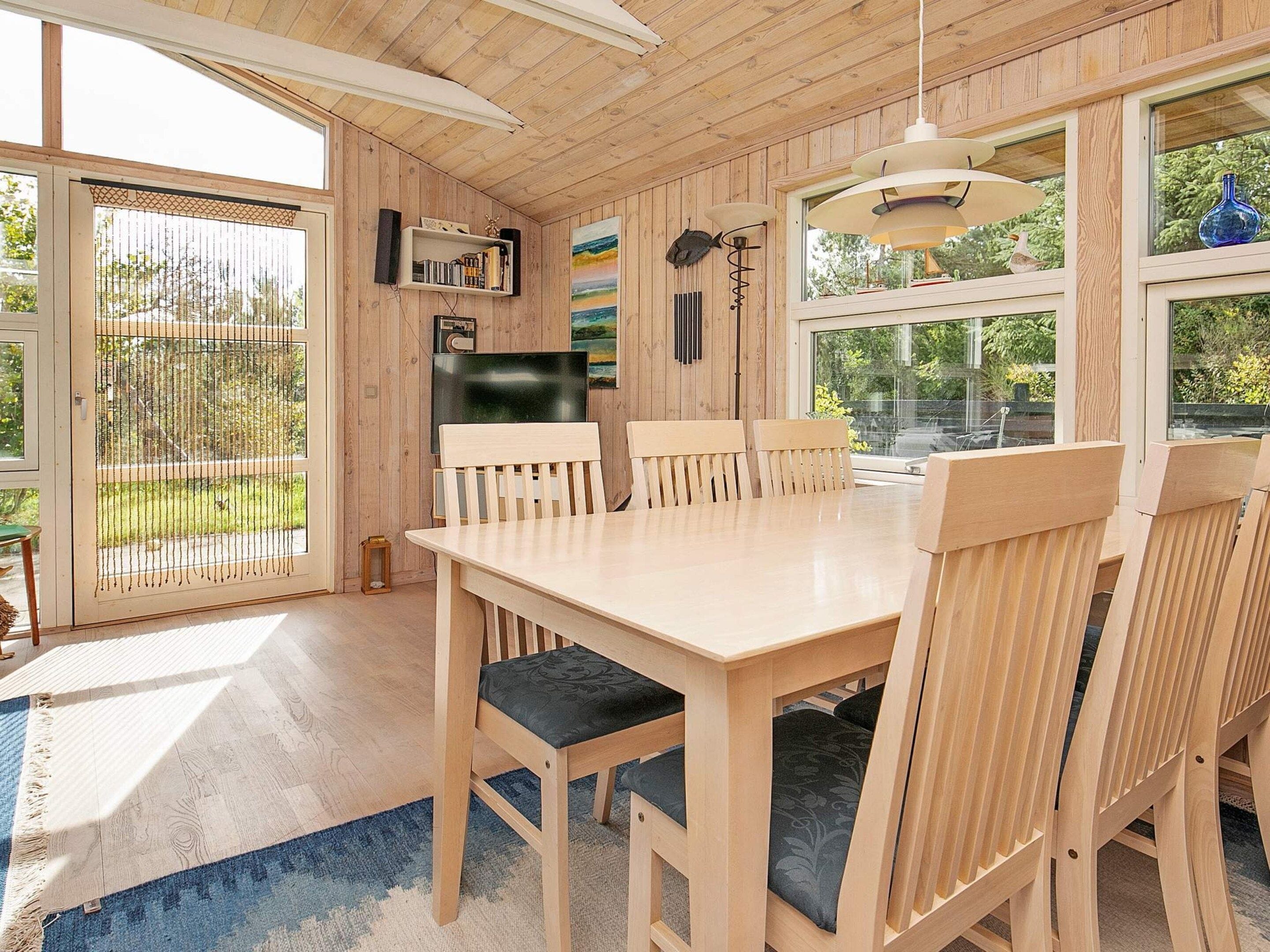 Un intérieur en bois comprenant une table et des chaises, un téléviseur et une bibliothèque.