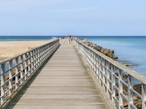 A wooden pier extending into the sea with railings on both sides.