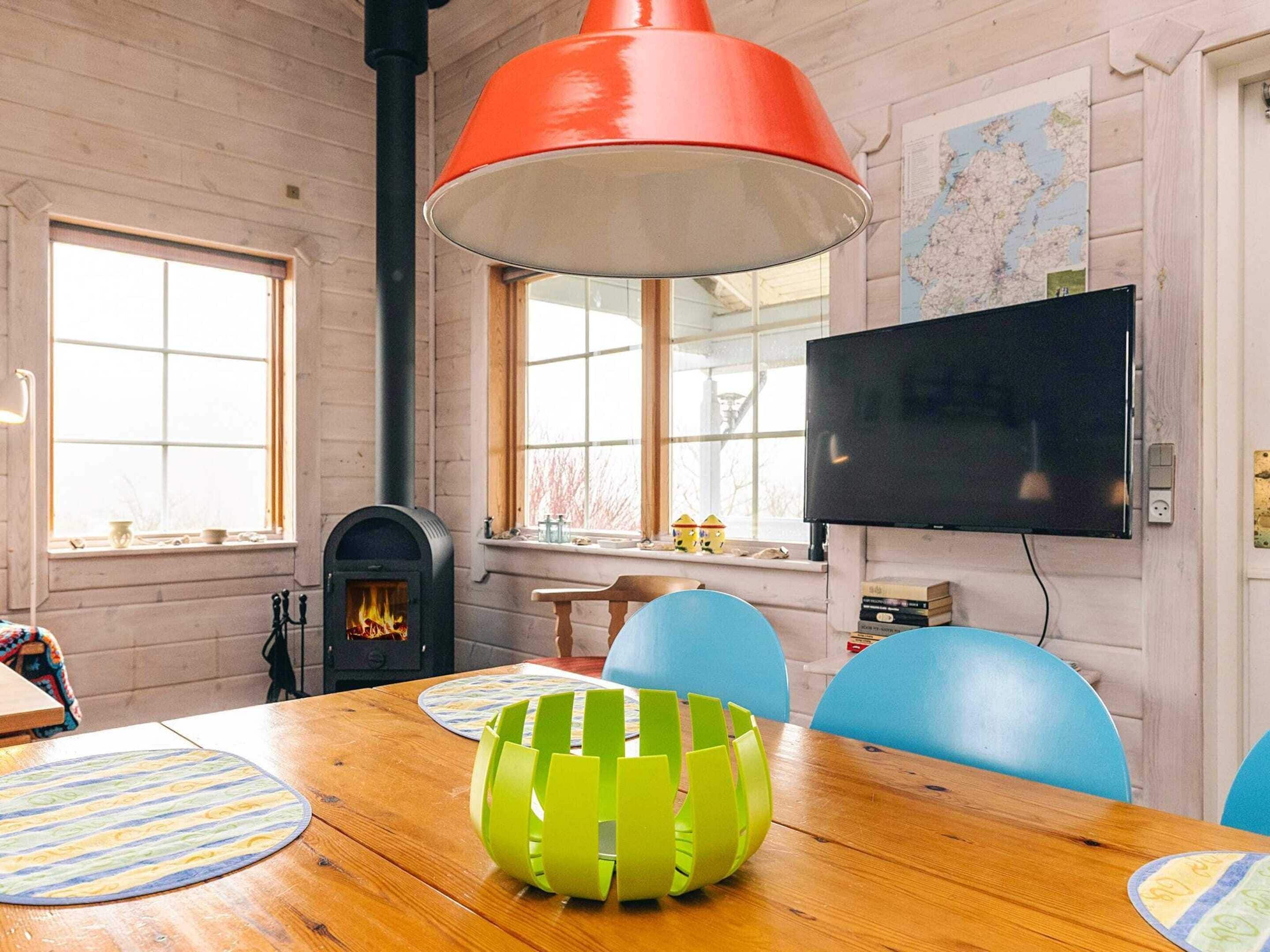 A room with a wooden table, chairs, a fireplace, a television, and a map on the wall.
