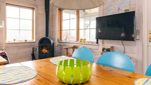 A room with a wooden table, chairs, a fireplace, a television, and a map on the wall. - 6 Person Holiday Home in Roslev (Roslev)